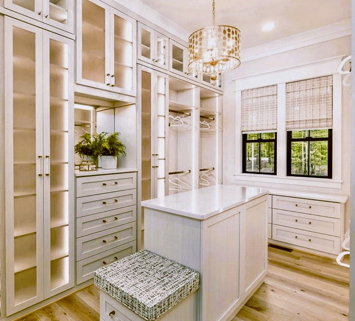 Walk-in closet with glass-front cabinets, a center island, a bench and a chandelier