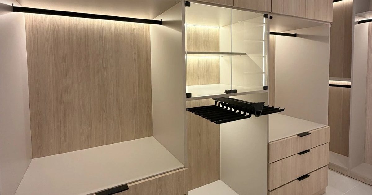 Finished luxury walk-in closet in Orlando with custom wood cabinetry, a center island, and warm integrated lighting
