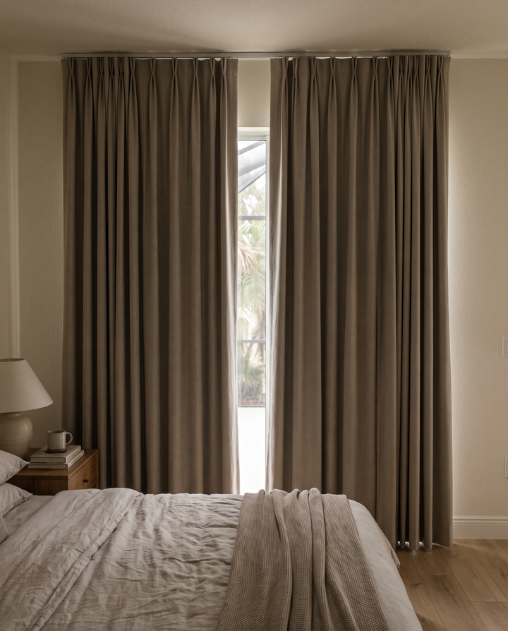 Taupe blackout drapes on a ceiling track in a bedroom