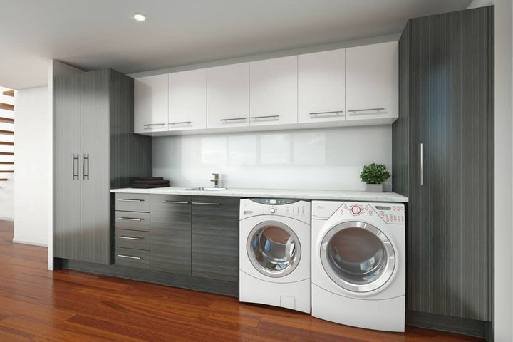Laundry room with gray and white cabinets around a front-load washer and dryer